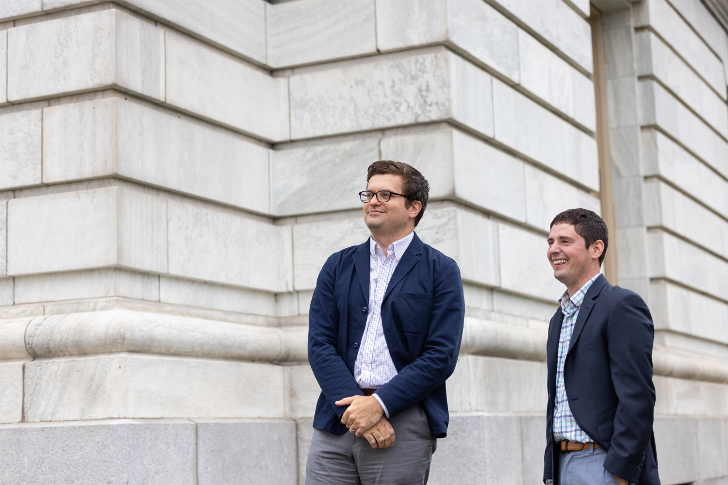 Two business professionals standing next to a granite building